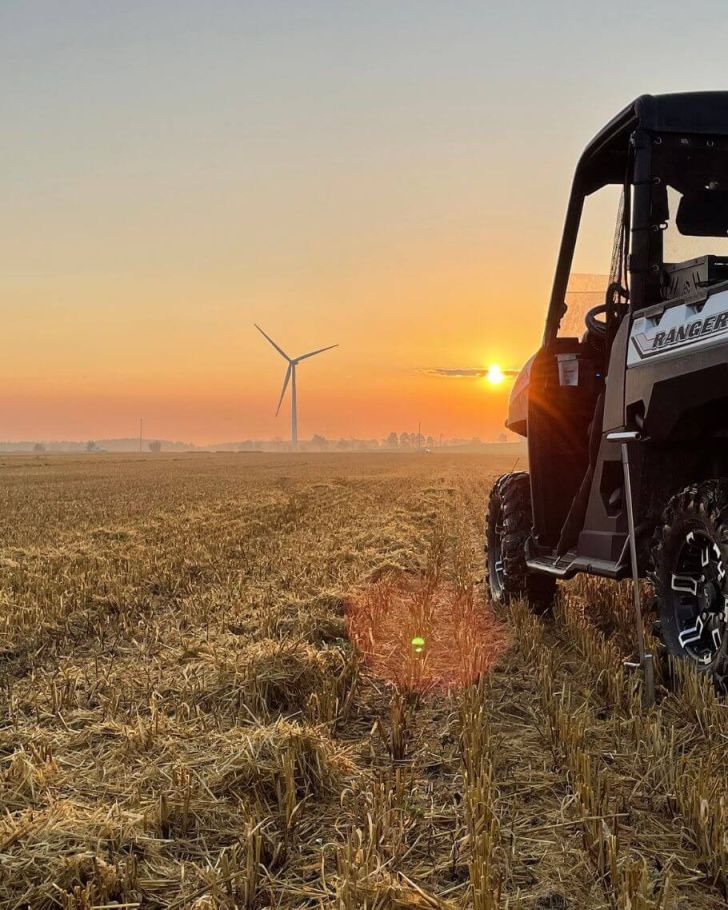 Holmes Agro Ranger on crop with windmills and sunset in the background