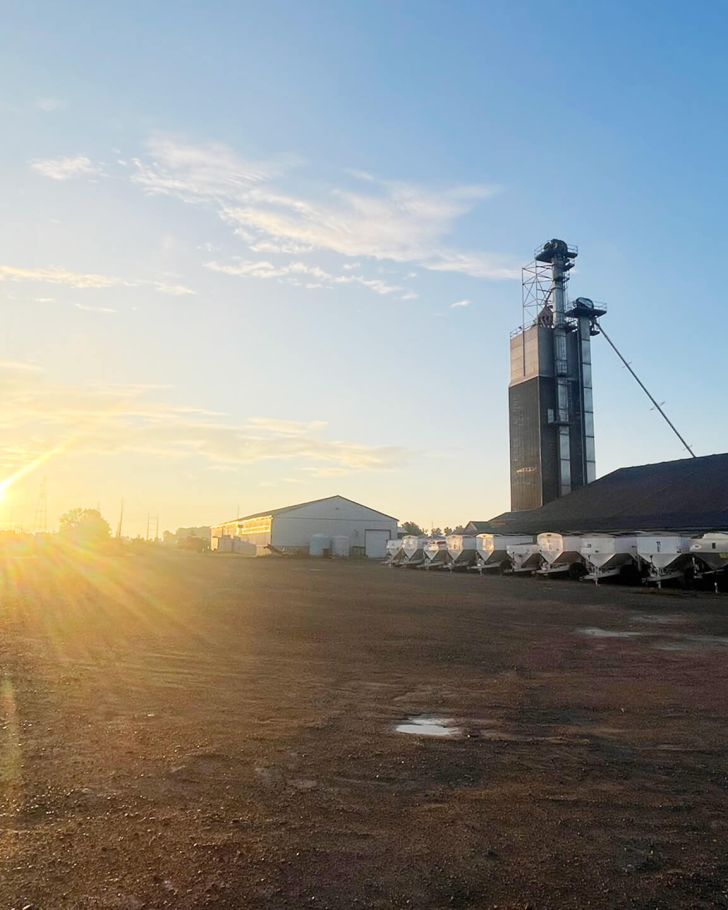 Holmes Agro lot with farming equipment and sunset in the background