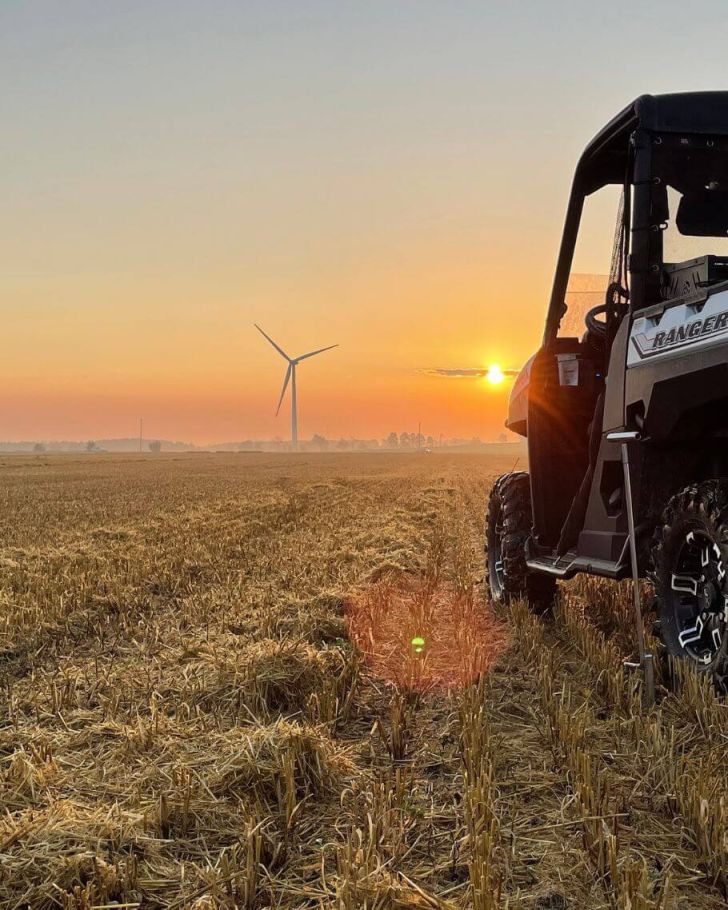 Holmes Agro Ranger on crop with windmills and sunset in the background
